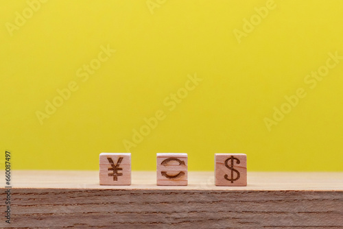 円とドルをマークしたウッドキューブを交換する机の上の黄色い背景の正面