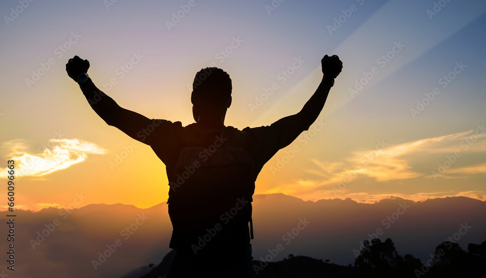 Silhouette of positive man standing on top of the mountain peak with arms raised celebrating his success.Success, victory and winning concept.