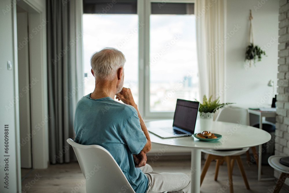 Senior man in wheelchair working from home during retirement. Elderly man using digital technologies, working on laptop. Concept of seniors and digital skills. Senior man in wheelchair working from home during retirement. Elderly man using digital technologies, working on laptop. Concept of seniors and digital skills.