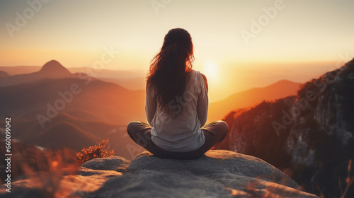 A woman meditates peacefully at sunset, with a blurred background, conveying relaxation and mental well-being. © B & G Media