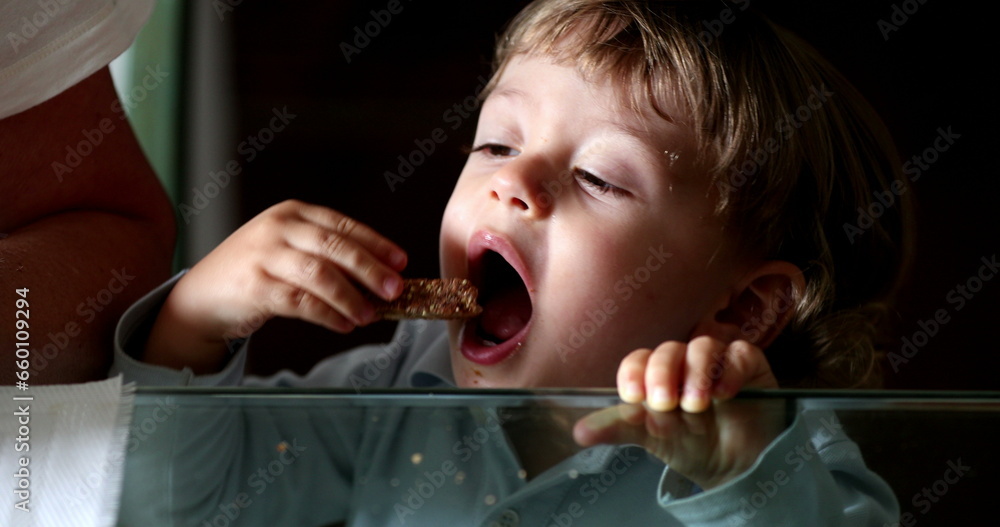 Child snacking bread and butter. Baby boy leaning on glass table grabbing food Child snacking bread and butter. Baby boy leaning on glass table grabbing food