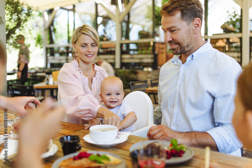 Family with baby in high chair eating food at restaurant. Family with baby in high chair eating food at restaurant.
