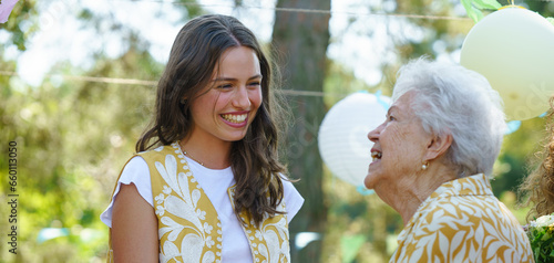 Mature granddaughter and grandmother reunite after a long time, talking. Family gathering at a garden party. Banner with copy space.