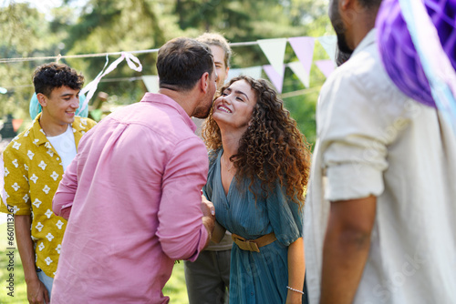 Friends reunite after a long time apart. Men and women embracing, happy to meet at garden party. photo