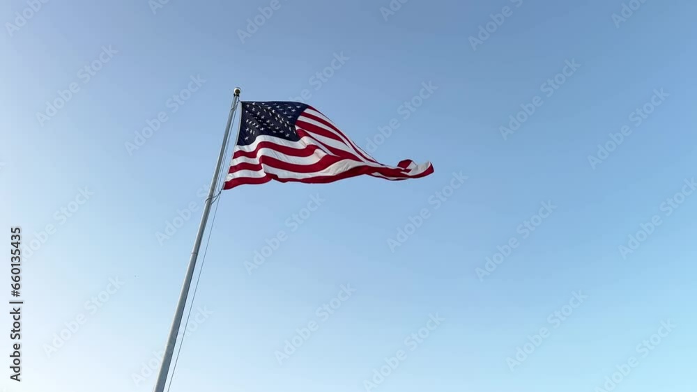 US American flag waving in the wind with a blue sky in background US American flag waving in the wind with a blue sky in background