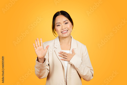 Photography Asian millennial woman swears, raising hand in studio, standing against a vivid