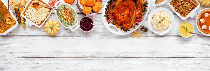 Traditional Thanksgiving turkey dinner. Overhead view top border on a rustic white wood banner background. Turkey, mashed potatoes, stuffing, pumpkin pie and sides.