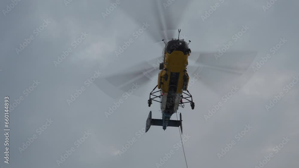 Helicopter lifts cargo on cable. Rope is attached to bottom of helicopter. Front view from below Helicopter lifts cargo on cable. Rope is attached to bottom of helicopter. Front view from below