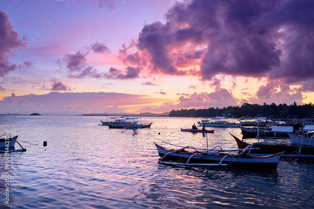 Beautiful colorful sunset on the seashore with fishing boats. Philippines, Siargao Island.