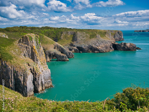 Coastal cliffs near Giltar Point in Pembrokeshire, Wales, UK - the vertically inclined rock strata of the limestone bedrock is of the Pembroke Limestone Group. Taken on a sunny day with a calm, sea.