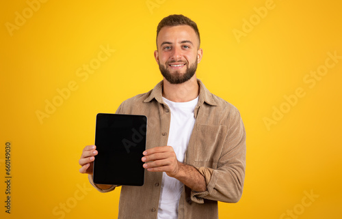 Positive millennial european guy show tablet with blank screen for marketing