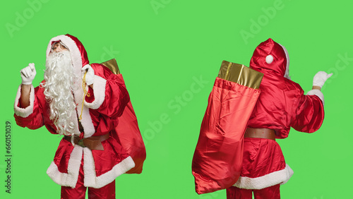 Saint nick bandmaster chief in costume accompany professional orchestra as choir musician, standing over greenscreen. Santa claus with gifts bag playing band music, musical conductor.