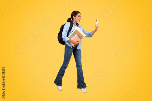 Student has fun while studying, using phone on a vibrant, colorful background