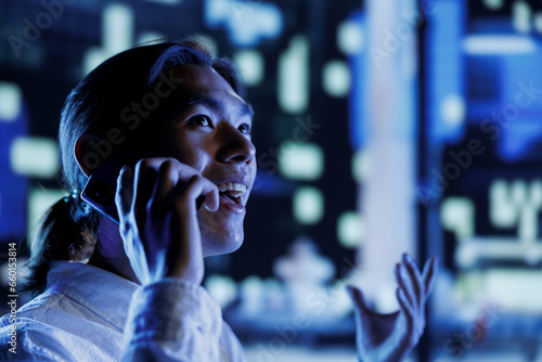 Happy man strolling around cityscape during nighttime, enjoying discussion over the phone with girlfriend, close up. Asian citizen making telephone calls while commuting, blurry background