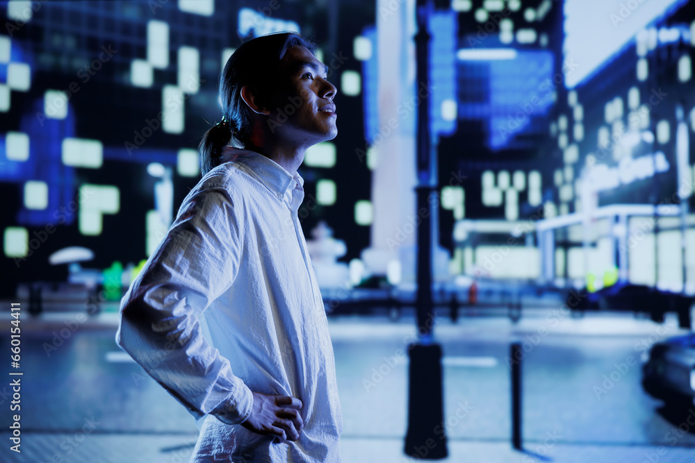 Asian man wandering around city boulevards during nighttime, being amazed by urban landscape buildings. Citizen strolling around empty avenues at night, enjoying street lamps illuminated surroundings Asian man wandering around city boulevards during nighttime, being amazed by urban landscape buildings. Citizen strolling around empty avenues at night, enjoying street lamps illuminated surroundings