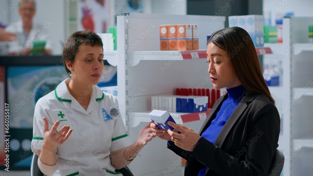 Experienced pharmacist in drugstore with patient prescribing her medical products to treat disease symptoms. Asian woman receiving medical indications from healthcare practitioner