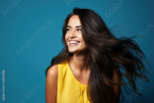 portrait of smiling young woman laughing against blue background