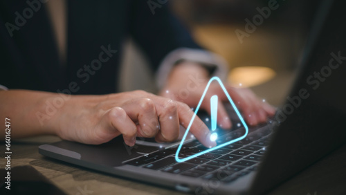 Businesswomen using computer laptop or tablet with triangle caution warning sign for notification error and maintenance concept. photo