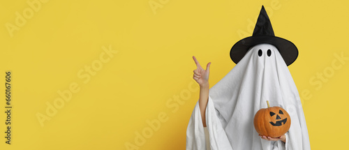 Fotografia Person in costume of ghost holding Halloween pumpkin and pointing at something o