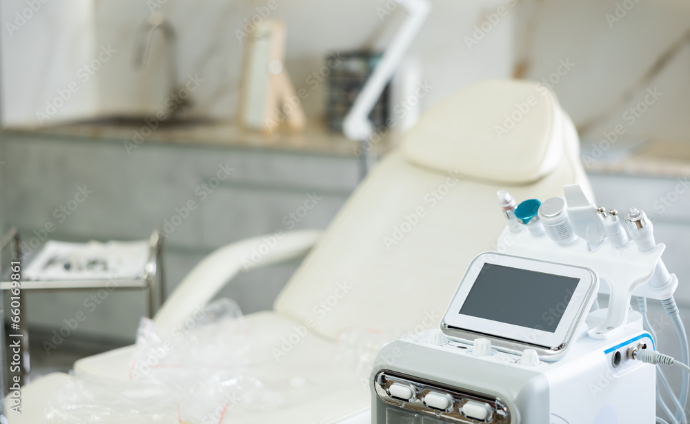 Interior of beauty treatment room with comfortable chair for patient and hydrogen-oxygen machine with various attachments for anti-aging procedures for facial and body skin care in cosmetology clinic