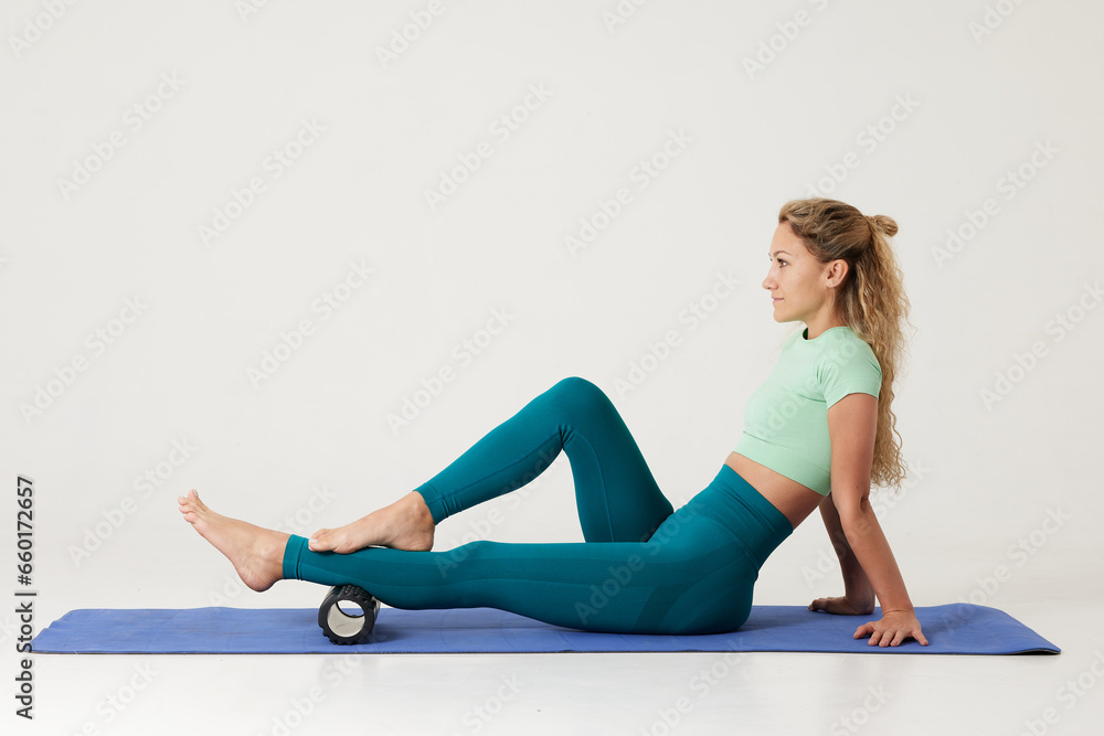 girl doing exercises on a roller and doing yoga on a white background, massage roller for fitness and yoga, Home training girl doing exercises on a roller and doing yoga on a white background, massage roller for fitness and yoga, Home training
