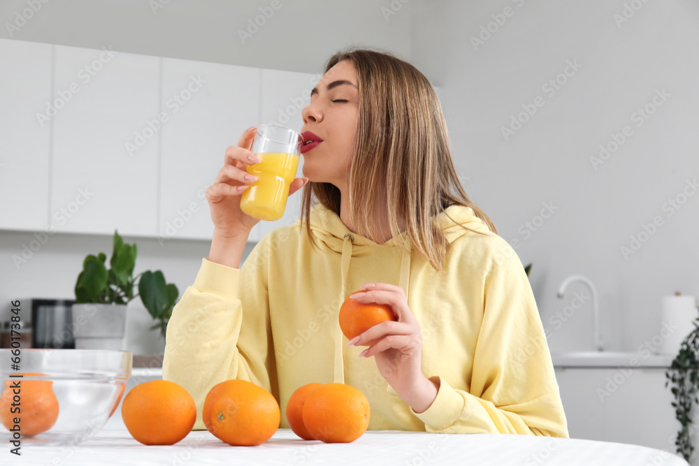 Young woman with glass of orange juice in kitchen Young woman with glass of orange juice in kitchen