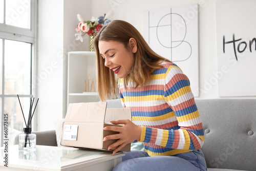 Young woman opening parcel ...