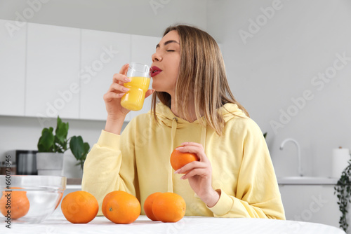 Young woman with glass of orange juice in kitchen