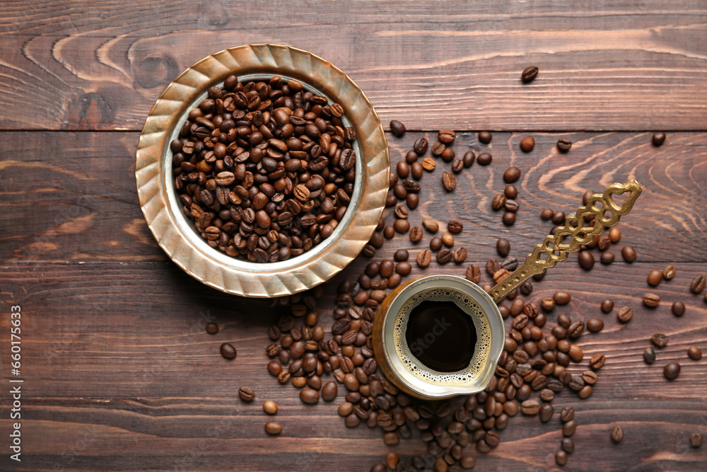 Coffee in cezve with scattered beans on brown wooden background Coffee in cezve with scattered beans on brown wooden background