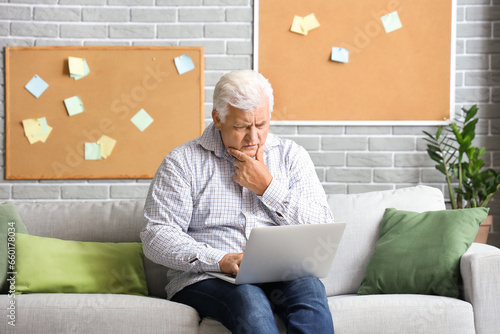Thoughtful senior man using...