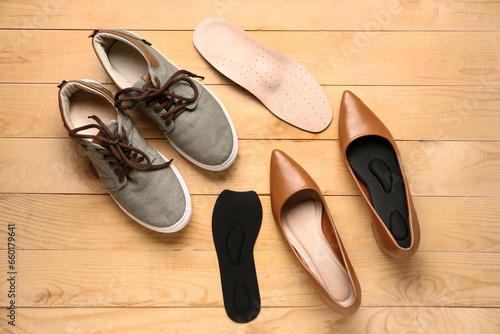 Stylish shoes and orthopedic insoles on wooden background