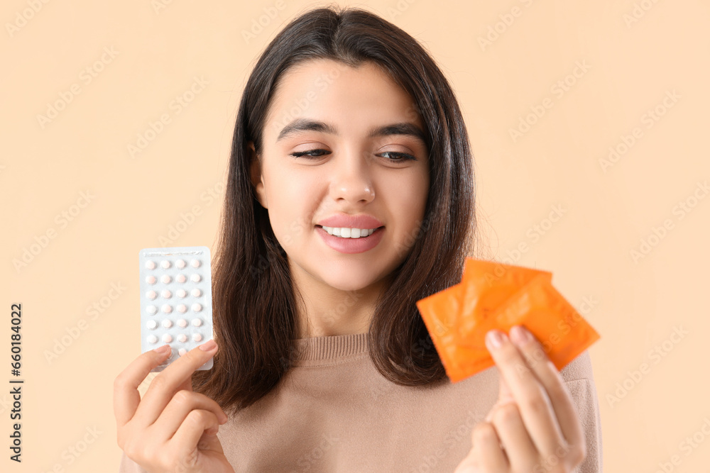 Young woman with condoms and birth control pills on beige background Young woman with condoms and birth control pills on beige background