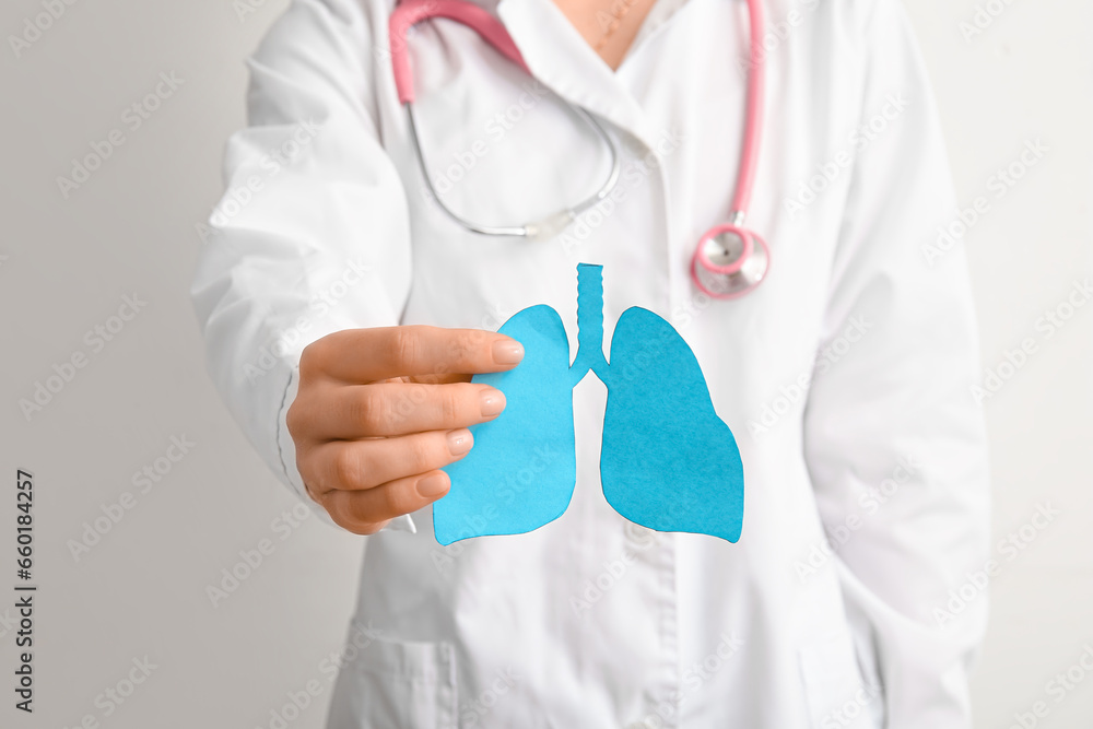 Doctor holding blue paper lungs on light background. Cancer concept Doctor holding blue paper lungs on light background. Cancer concept