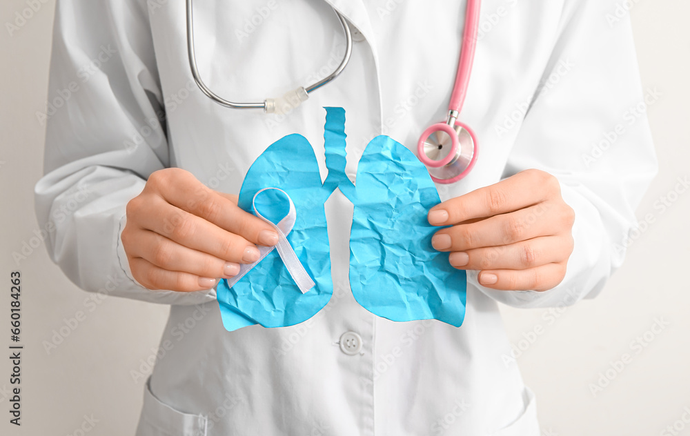Doctor holding blue paper lungs on light background. Cancer concept Doctor holding blue paper lungs on light background. Cancer concept