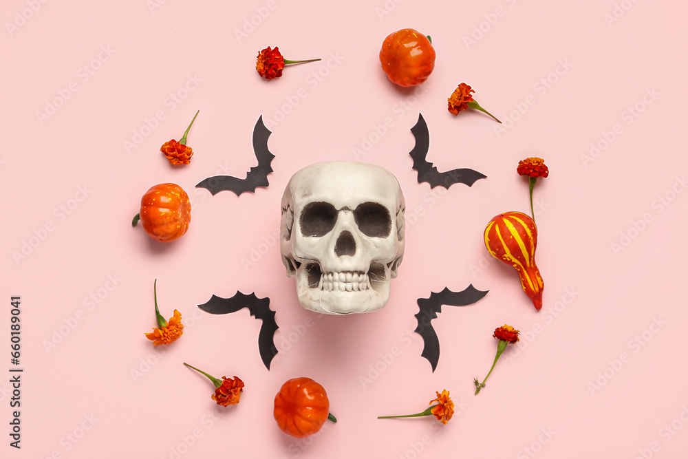 Human skull with marigold flowers, bats and pumpkins on pink background Human skull with marigold flowers, bats and pumpkins on pink background