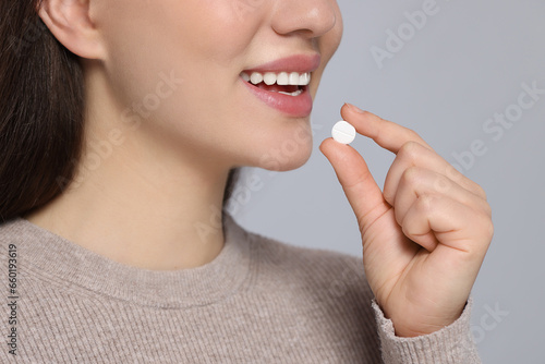 Woman taking pill on gray background  closeup