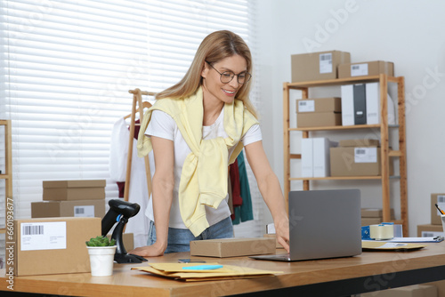 Seller with parcel and laptop working in office. Online store