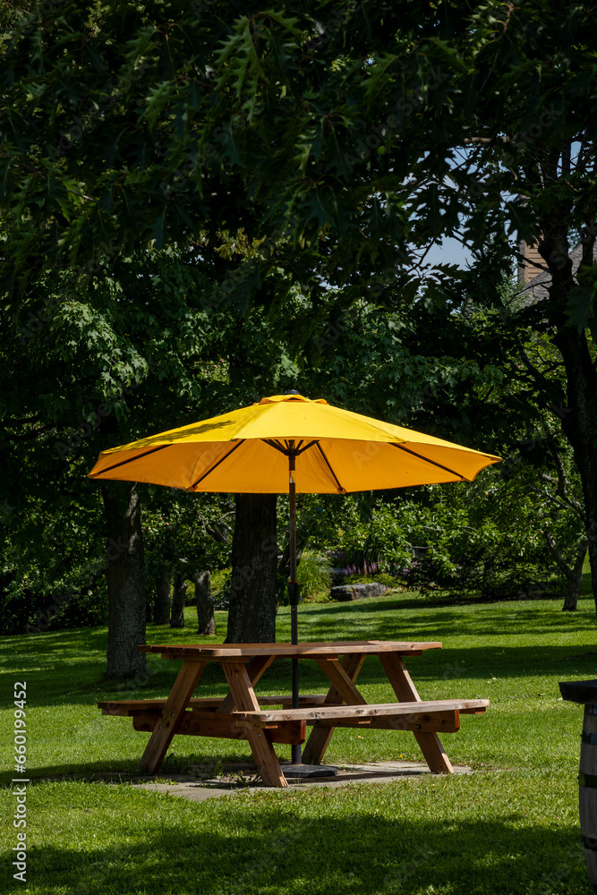 rural landscape with wooden table with benches and yellow umbrella on a farm in Canada.