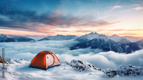 Orange tent in the snow with mountains and sunset in the background photo