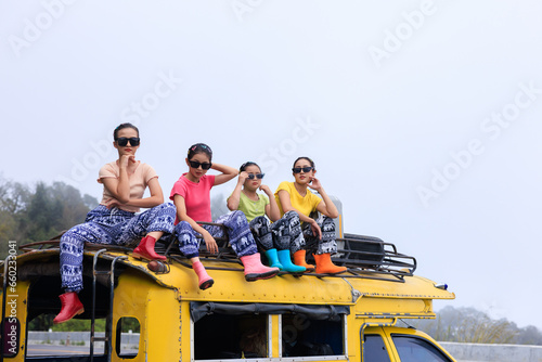  teenager girl friends group sitting on the roof of yellow a minibus, chiamg mai thailand, amazing travel tourist concept, photo