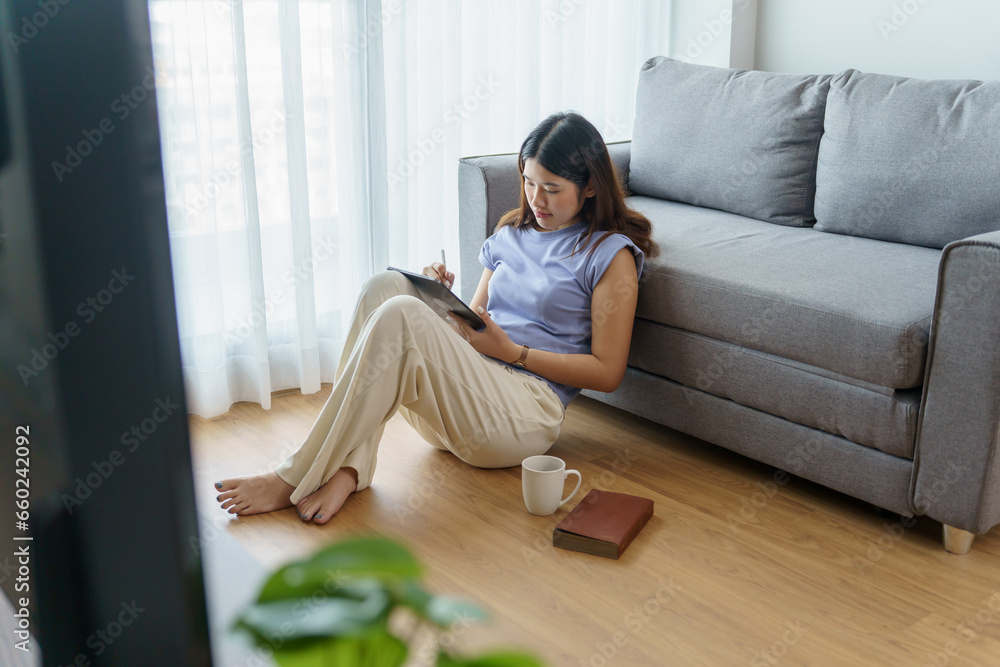 Obraz premium Woman holding a book device reading on e-book on digital tablet device or social media apps online ecommerce