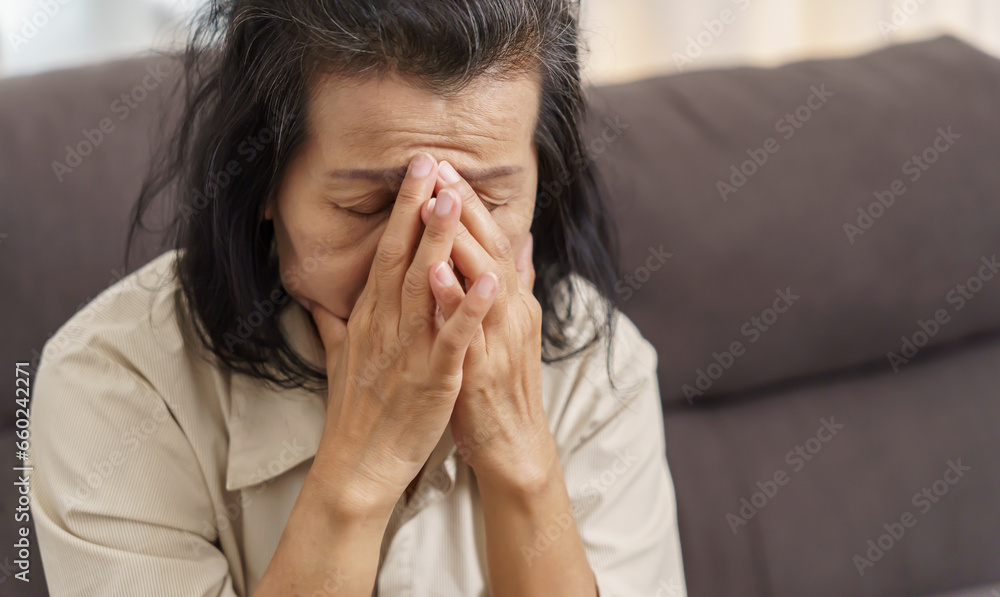 Sad middle age Asian woman touching forehead having headache suffering from migraine. mature asian woman feeling sick or depression. Sad middle age Asian woman touching forehead having headache suffering from migraine. mature asian woman feeling sick or depression.