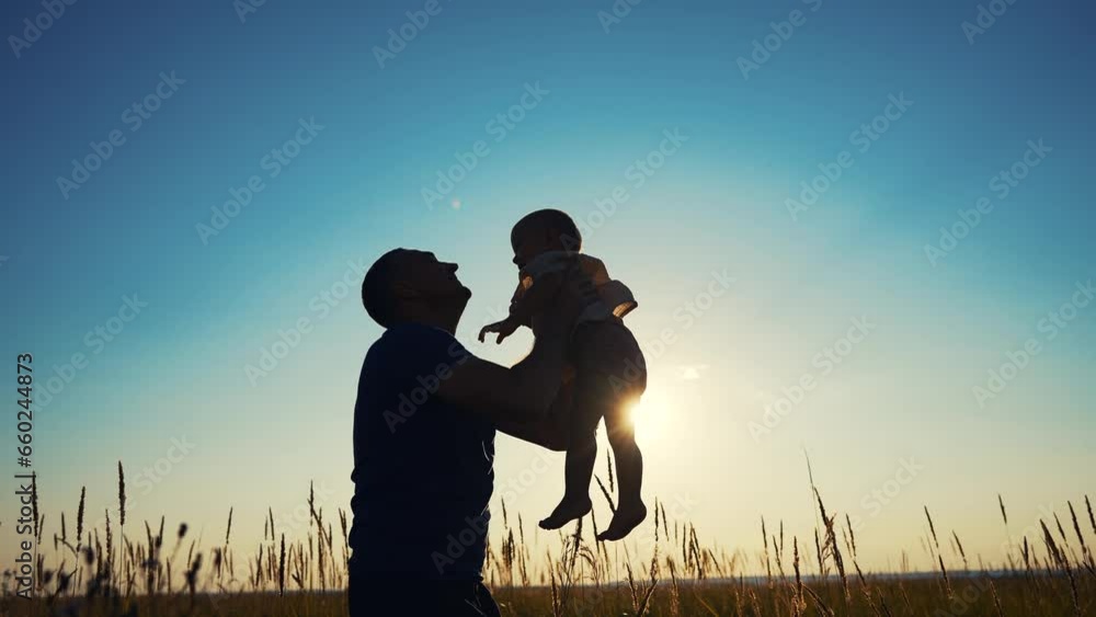father throws play baby in the park. father's day silhouette happy