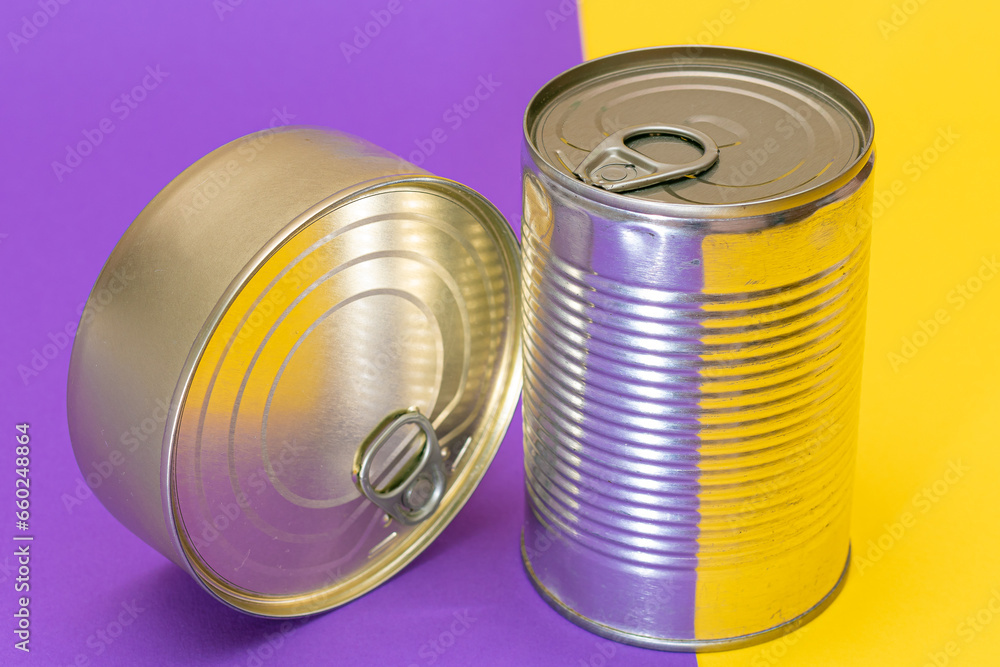 A Group of Stacked Tin Cans with Blank Edges on Split Yellow and Violet Background. Canned Food. Different Aluminum Cans for Safe and Long Term Storage of Food. Steel Sealed Food Storage Containers A Group of Stacked Tin Cans with Blank Edges on Split Yellow and Violet Background. Canned Food. Different Aluminum Cans for Safe and Long Term Storage of Food. Steel Sealed Food Storage Containers