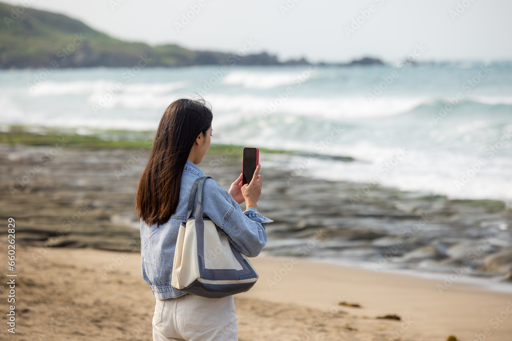 Woman use mobile phone to take photo on beach