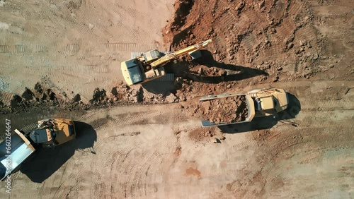 Drone top down shot of Excavator loads sand into mining truck. Mining Excavator loads sand rock into haul truck