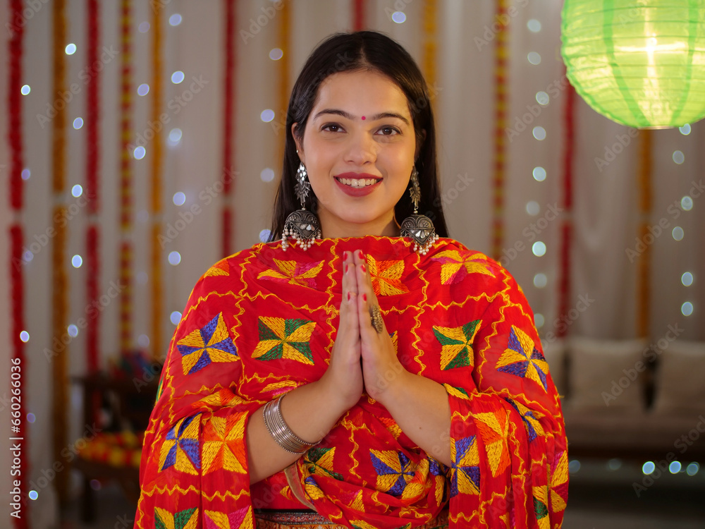 Pretty Indian woman in Namaskar position looking towards the camera - Diwali celebration  festival decoration. A beautiful woman in the traditional outfit in a greeting or welcoming gesture - smili...