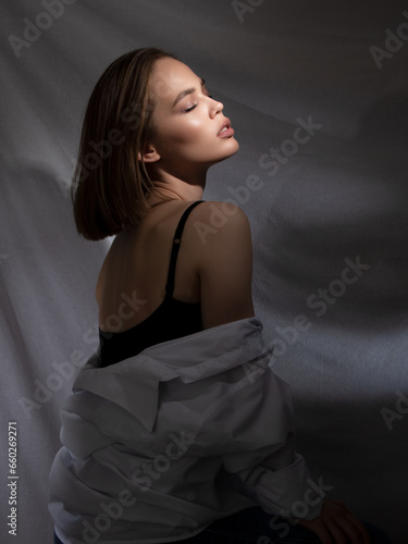 Beauty fashion model. Creative close-up portrait of a beautiful girl with eyeliner standing on stage with a beam of bright light