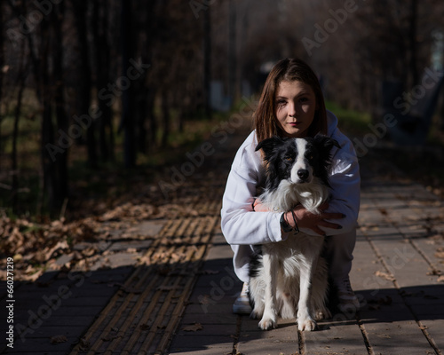 Caucasian woman hugging border collie in autumn park. Portrait of a girl with a dog. © Михаил Решетников