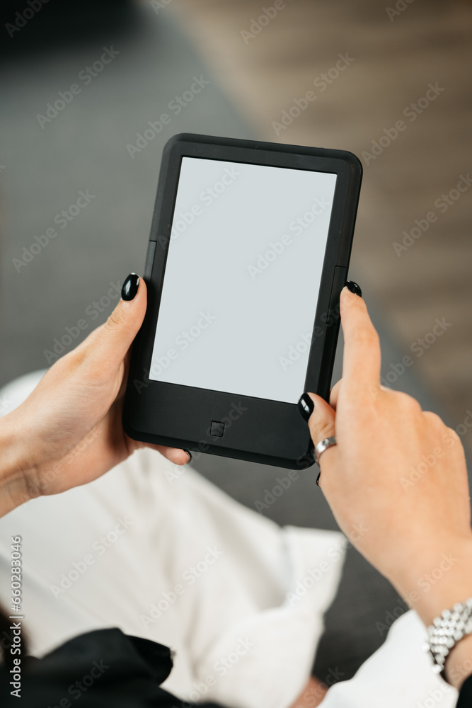 Young woman sitting the couch with an e-book